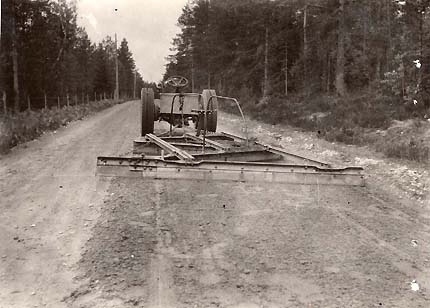 Kuvituskuva: mustavalkoinen vanha kuva, jossa traktori lanaa tietä.