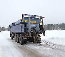 Hiekoitusauto levittää hiekkaa.