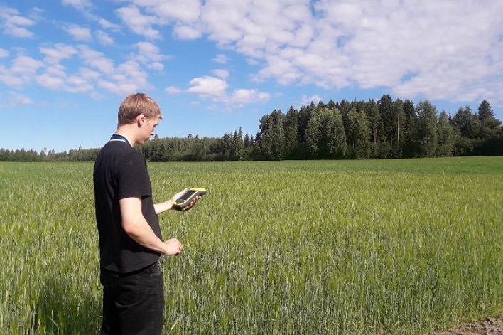 Nuori mies tekemässä peltovalvontaa gps-laitteella.