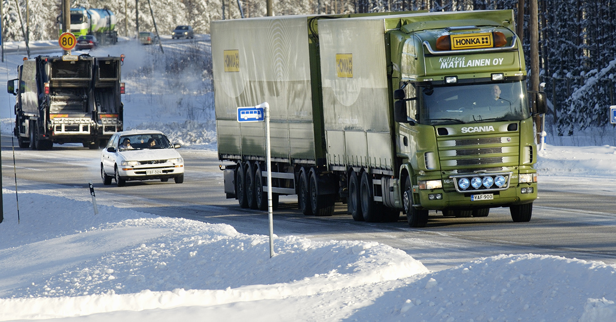 Talvinen kuva missä raskaan liikenteen rekka, sekä henkilöautoja. 