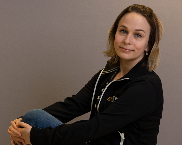 Maija Savolainen nojaa käsiinsä ja katsoo kameraan