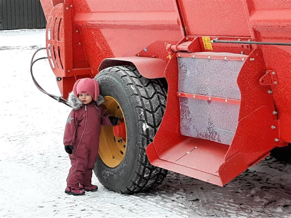 Pieni lapsi seisoo apevaunun renkaan vieressä.