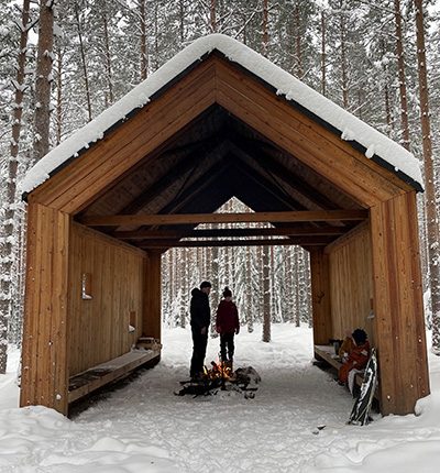 Ihmiset talvisäässä katetulla nuotiopaikalla.