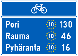 Sininen opastustaulu, johon EuroVelo 10 -reitti on merkitty keltaisten tähtien muodostamalla ympyrällä, jonka keskellä on valkoinen numero kymmenen.