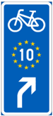 Sininen opastustaulu, johon EuroVelo 10 -reitti on merkitty keltaisten tähtien muodostamalla ympyrällä, jonka keskellä on valkoinen numero kymmenen.