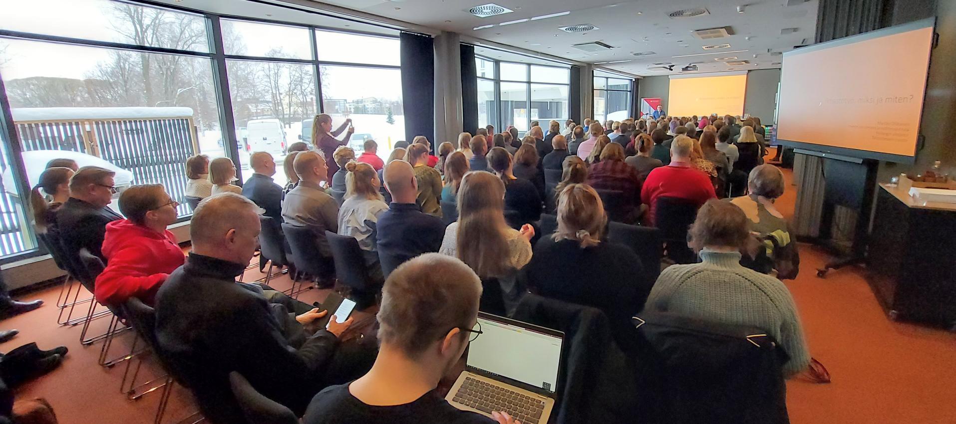 Ilmastokonferenssin osallistujia ja esiintymässä emeritusprofessori Ollikainen. Kuva Jon Norppa