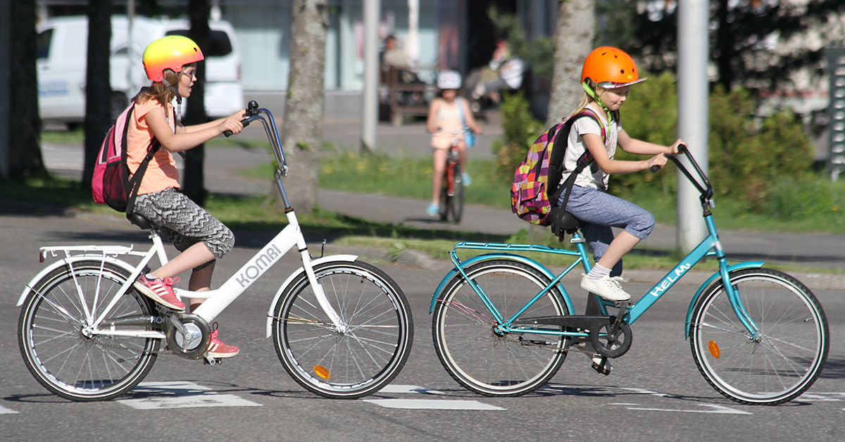 Kaksi lasta pyöräilemässä suojatiellä.