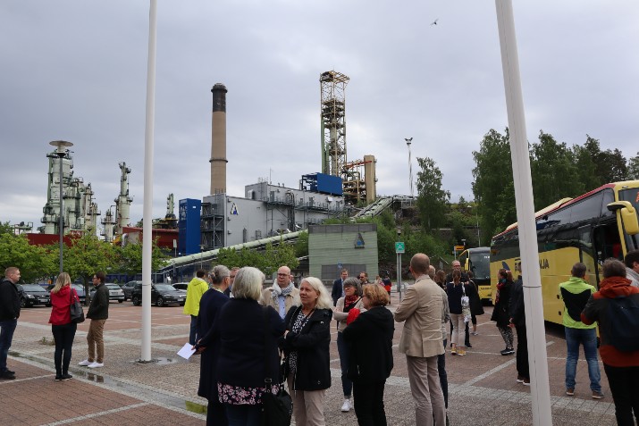 Ihmiset seisovat ulkona pienissä ryhmissä keskustelemassa.