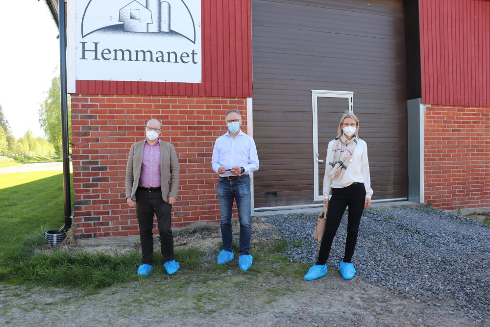 Tre pårsoner med ansiktsmaskerna på sig står framför en hus