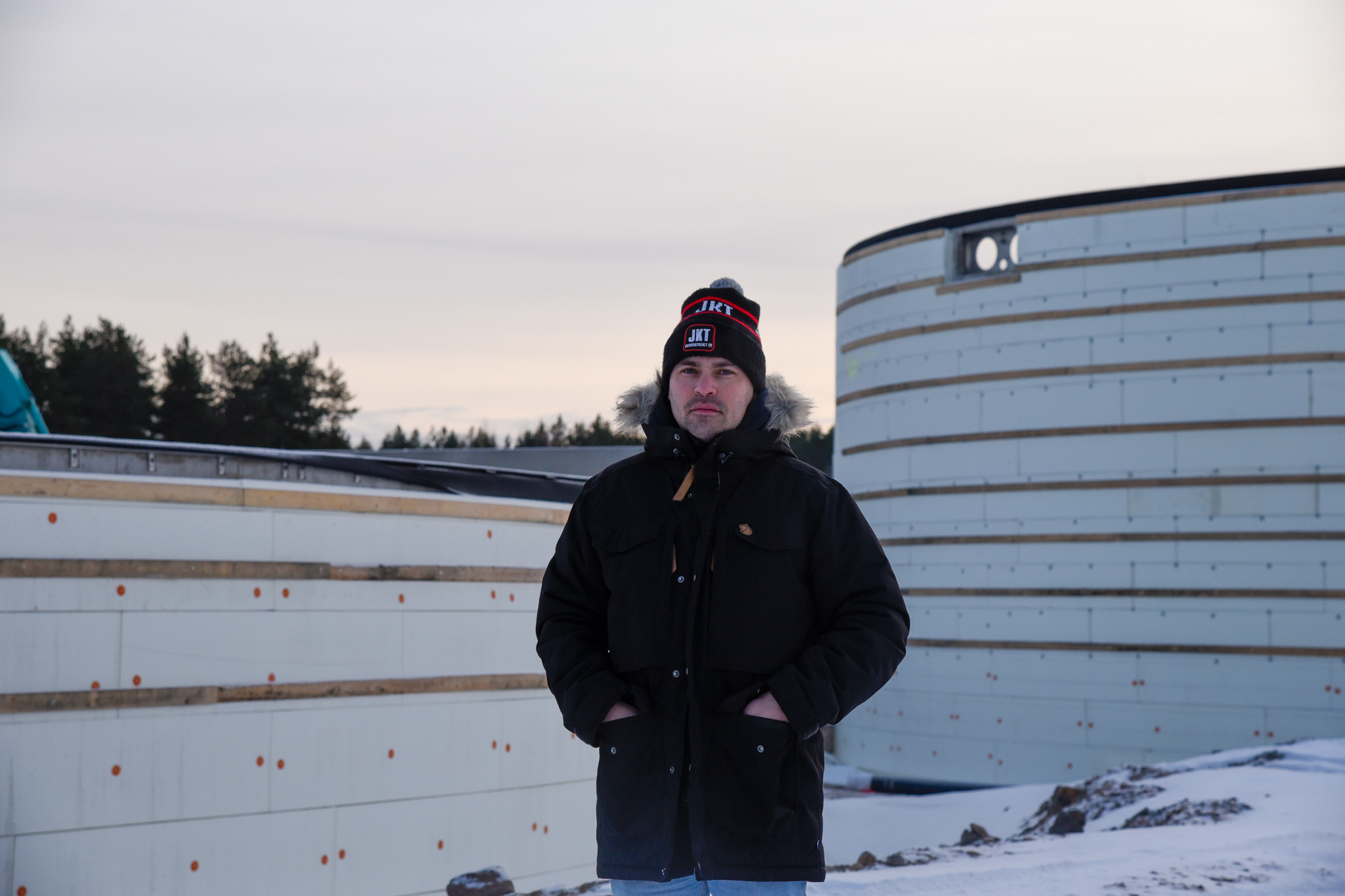 Tehtaanjohtaja Erkki Pisilä seisoo rakenteilla olevan biokaasulaitoksen edessä talvisessa maisemassa.