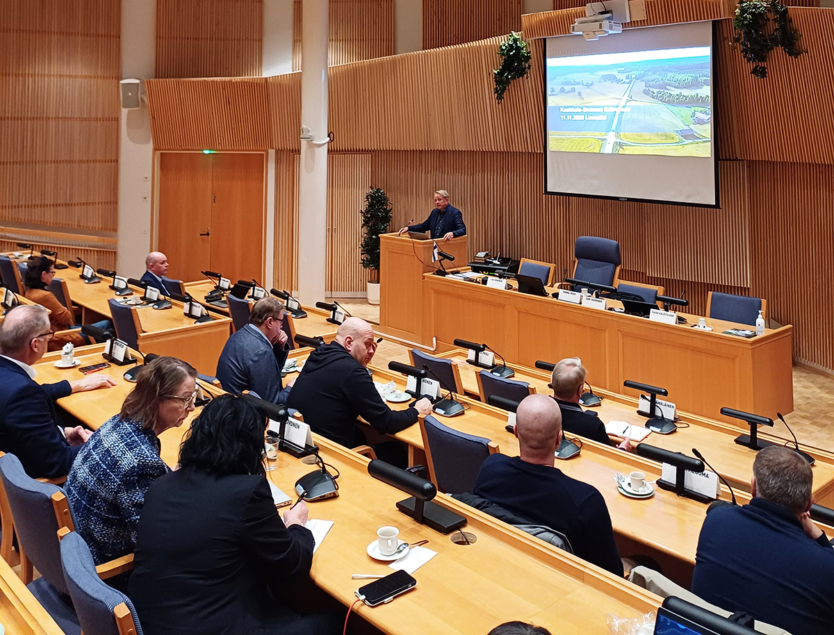 Ihmisiä istumassa valtuustosalissa ja puhuja on edessä.