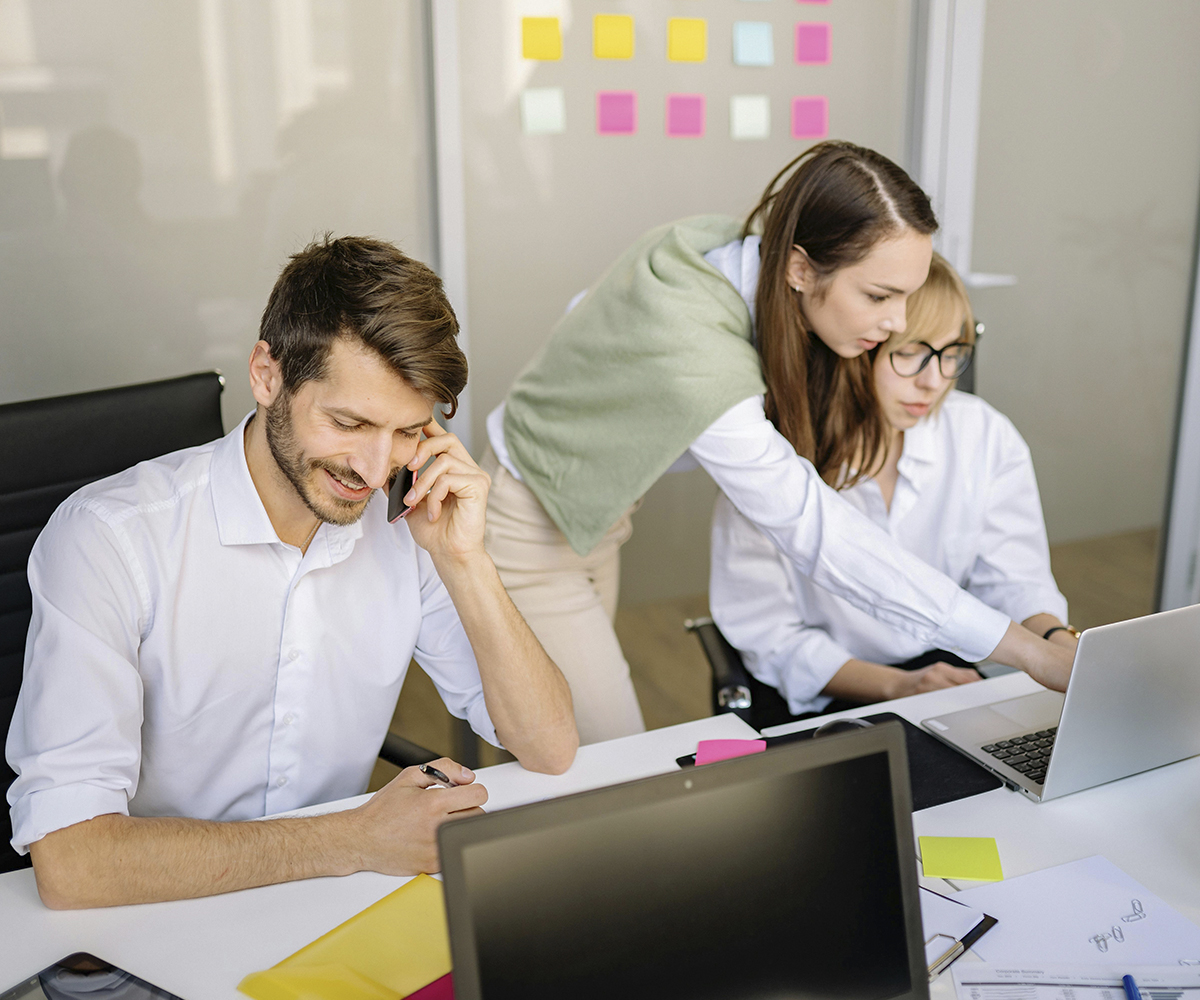 Tiimityöskentelyä tietokoneilla yhteisen pöydän ääressä.