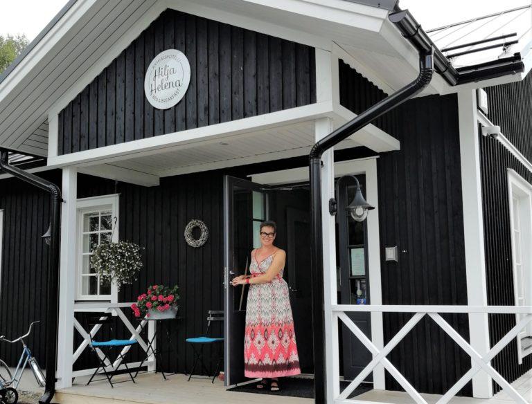 Yrittäjä Mari Seppänen seisoo HiljaHelena-matkustajakodin terassilla oviaukossa. 
