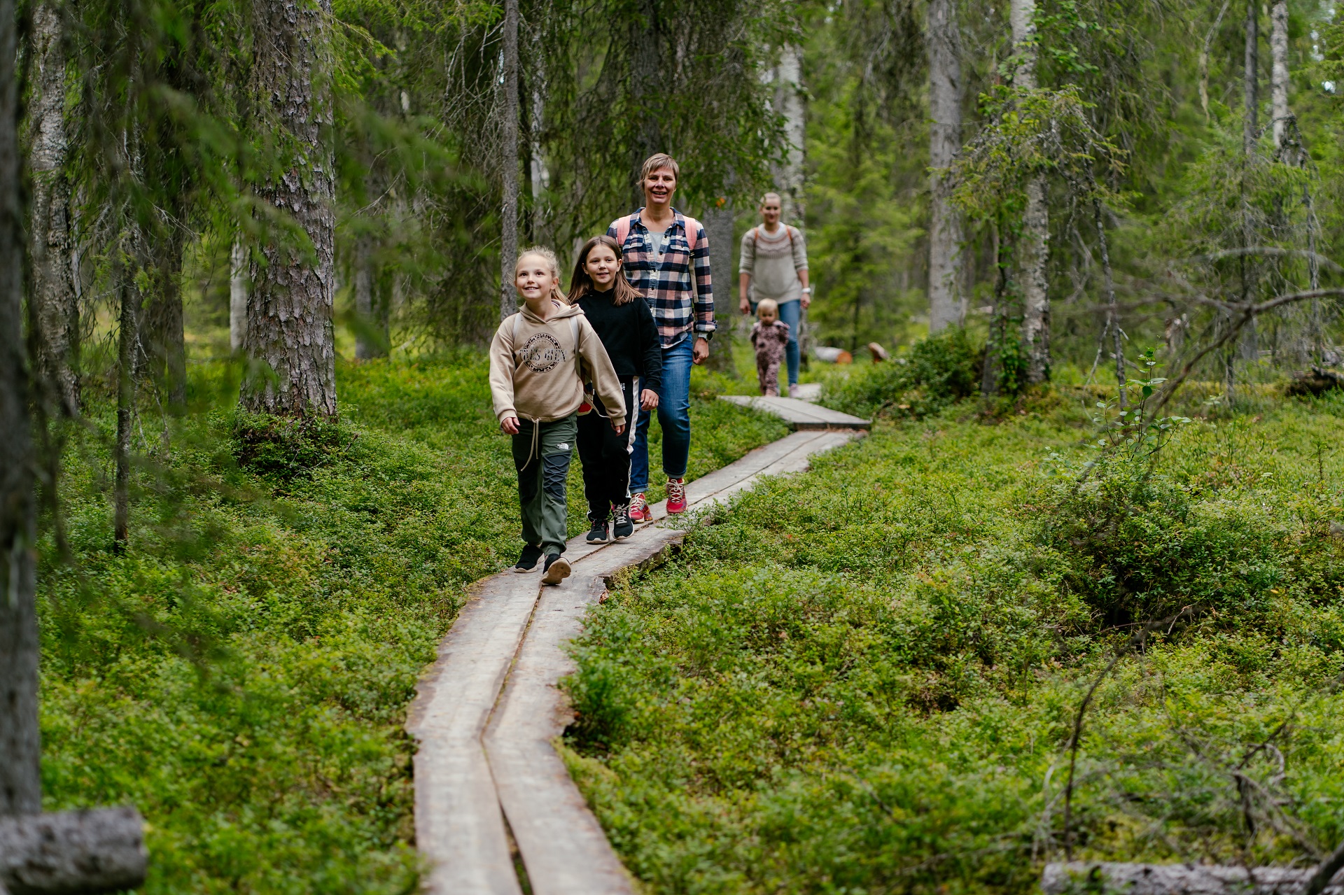 Yläkemijoella voi nauttia luontoretkistä, kokea erilaisia elämyksistä ja nauttia maanläheisestä tekemisestä. Auttikönkään luontopolku kulkee kuohuvien koskien ja vanhojen metsien läpi. Kuvassa perhe kävelee metsässä pitkospuita pitkin. 