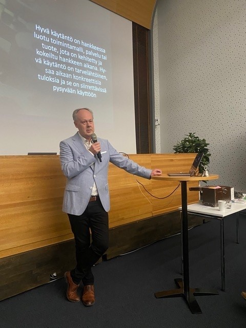 Timo Aro seisoo mikrofoni kädessään.