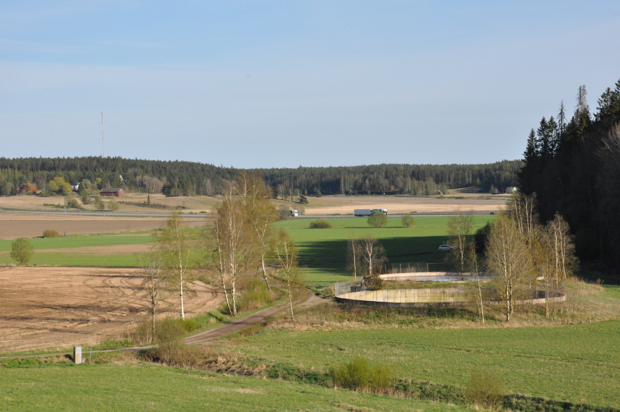 Peltomaisema, jonka keskellä kaksi laskeutusallasta. Peltojen oikealla puolella metsää ja taustalla näkyy moottoritie.